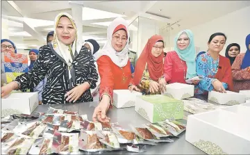  ??  ?? Fatimah (second left) helps others in packing the cakes and biscuits at Wisma Wanita in Kuching.