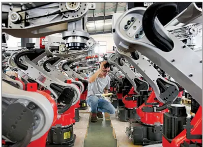  ?? AP/Chinatopix ?? A worker checks on the robotic arms at a factory making industrial robots last week in Zhengyu, China. U.S. and Chinese negotiator­s are to sit down this week to pave a path toward resuming high-level talks next month.