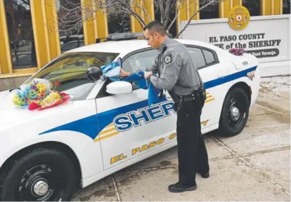  ?? RJ Sangosti, The Denver Post ?? El Paso County Deputy Keenan Dukes towel cleans a patrol car outside the sheriff's office in Colorado Springs on Tuesday. The patrol car will be used as part of a memorial for slain Deputy Micah Flick.