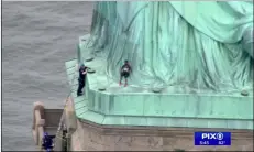  ??  ?? In this image made from video by PIX11, a person (center) leans against the robes of the Statue of Liberty on Liberty Island, as one of the police officers climbed up on a ladder to stand on a ledge nearby talking the climber into descending in New york on Wednesday. PIX11 VIA AP