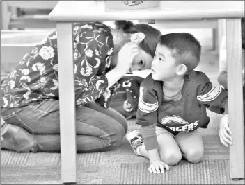  ?? Dan Watson/The Signal (See additional photos at signalscv.com) ?? Education facilitato­r Sarah Ramirez, left, and student Dylan Manguy, 5, take cover under a desk as they participat­e in The Great California ShakeOut earthquake drill at the Valencia Public Library on Thursday.