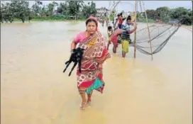  ?? PTI PHOTO ?? A woman walks to a safer place as many others catch fish at the flooded village of Srilanka Basti in Agartala on Tuesday.