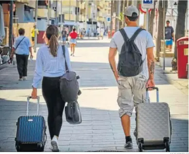  ?? JULIO GONZÁLEZ ?? Varios turistas andan con sus maletas por el Paseo Marítimo de la capital.