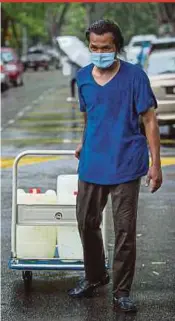  ?? PIC BY AZIAH AZMEE ?? A man carting water barrels on a trolley in Shah Alam yesterday.