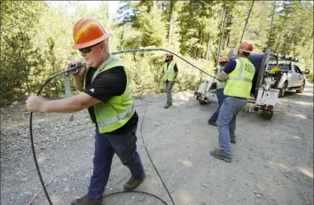  ?? AP ?? Carl Roath, left, a worker with the Mason County (Wash.) Public Utility District, pulls fiber optic cable off a spool. He was working with a team to install broadband internet service to homes in a rural area surroundin­g Lake Christine near Belfair, Wash., last year.