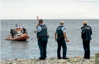  ?? BRADEN FASTIER/STUFF ?? Police investigat­e the scene where a ute drove off Boulder Bank Drive into the sea.