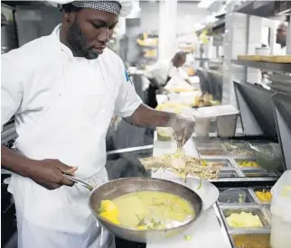  ??  ?? Jojo Restaurant assistant chef Gedeon Jean prepares fish in spiced broth in Petionvill­e, Haiti.