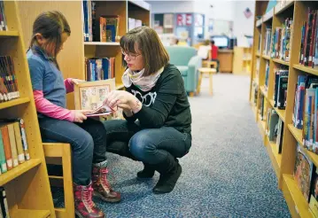  ??  ?? Gonzales Community School librarian Kelly McCabe helps Olvia Santos, 6, find a book to read. McCabe, who tailors her lesson plans to complement what students are learning in class, says for the kids, library time ‘gives them choice and the chance to...