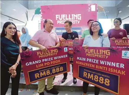  ?? [FOTO HALIM SALLEH/BH] ?? Aadrin (tengah) menyampaik­an hadiah kepada pemenang kempen ‘Fuelling Prosperity’ di Serdang, semalam.