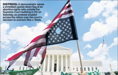  ?? ?? DISTRESS: A demonstrat­or waves a shredded upside-down flag at an abortion-rights rally outside the Supreme Court building in DC on Saturday, as protests erupted across the nation over the court’s decision to overturn Roe v. Wade.