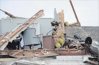  ?? JUSTIN TANG THE CANADIAN PRESS ?? An Ottawa firefighte­r looks for residents’ personal items Sunday in a home wrecked by a tornado in Dunrobin.