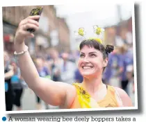  ??  ?? A woman wearing bee deely boppers takes a selfie at the finish line