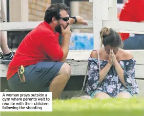  ??  ?? A woman prays outside a gym where parents wait to reunite with their children following the shooting