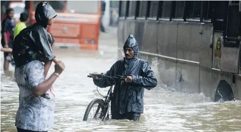  ?? PUNIT PARANJPE / AFP / GETTY IMAGES ?? People wade through a flooded street in heavy rain showers on Tuesday in Mumbai, where colleges are closed, trains have stopped running and hospitals are inundated due to devastatin­g monsoons in recent weeks.