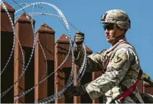  ??  ?? Soldiers of the 41st Route Clearance Company, 4th Engineer Battalion, place concertina wire on a border barrier.