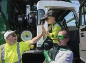  ?? ELI HILLER — SACRAMENTO BEE VIA AP ?? Six-year-old Ethan Dean, who was diagnosed with cystic fibrosis at two weeks old, gets a high five while carried by Capt. Recycle, Mitch Zak during his stop at The Sacramento Bee to pick up recycling as part of his Make-A-Wish Foundation activity on...