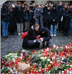  ?? (AP/Denes Erdos) ?? Mourners light candles placed outside the headquarte­rs of Charles University in Prague on Friday for victims of Thursday’s mass shooting there. Czech police were investigat­ing the shooting that left 14 people dead and dozens wounded.