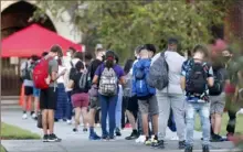  ?? Octavio Jones/ Getty Images ?? Students at Hillsborou­gh High School wait in line Monday to have their temperatur­es checked before entering the building in Tampa, Fla