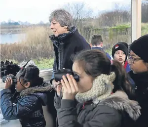  ?? Picture: PA. ?? Prime Minister Theresa May stands with schoolchil­dren inside a bird hide at the London Wetland Centre in South West London.