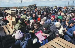  ?? NIKOLAI TRISHIN / TASS ?? Residents wait to receive humanitari­an aid outside a hypermarke­t in the city of Mariupol on Wednesday.