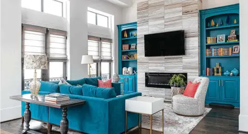  ?? Julie Soefer ?? Samantha Thompson and her interior designer, Pamela O’Brien, opted for a teal sofa with bookcases painted the same color. Bright pink pillows bring another color into the room.