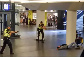  ??  ?? Dutch police officers point their guns at a wounded 19-year-old man who was shot by police after stabbing two people in the central railway station in Amsterdam, the Netherland­s, on Friday. AP Photo