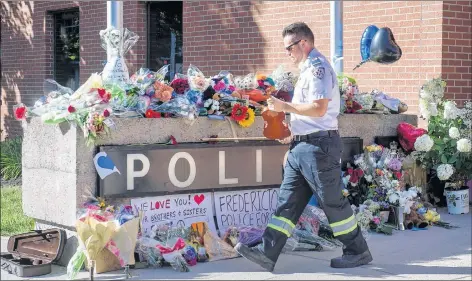  ?? CP PHOTO ?? Paramedic Brian Fournier walks away after playing a hymn and placing a tribute at the police station in Fredericto­n on Friday.