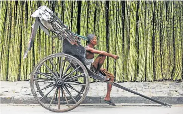  ?? /Reuters ?? Growing weary: A hand-rickshaw puller waits for customers at a roadside wholesale sugar cane market in Kolkata. The government has allowed the duty-free import of 500,000 tonnes of sugar by the end of June.