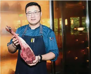  ??  ?? Controllin­g price hike: Stone Sal’s Lin holding a chunk of beef imported from the US at his restaurant in Shanghai. He and his US suppliers are eating the losses themselves rather than pass them on to customers — AFP