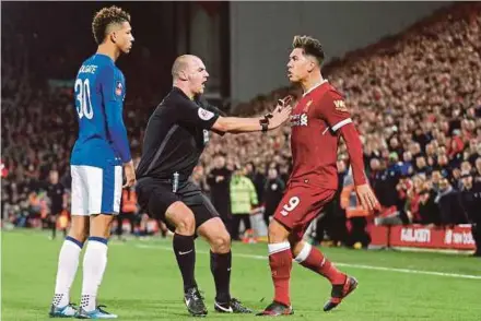  ?? REUTERS PIC ?? Referee Robert Madley attempts to separate Everton’s Mason Holgate (left) and Liverpool’s Roberto Firmino at Anfield on Friday.