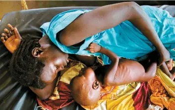  ??  ?? Une mère donne le sein à son bébé qui souffre de malnutriti­on dans une clinique.
