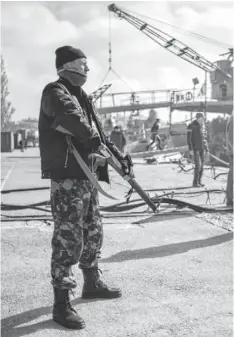  ?? ANDREW LUBIMOV, AP ?? An unidentifi­ed man stands guard Thursday during seizure of the Ukrainian ship Khmelnitsk­y in Sevastopol, Crimea.