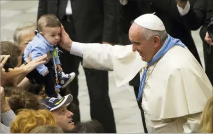  ?? THE ASSOCIATED PRESS ?? Pope Francis caresses a baby as he meets with members of the Italian Adult Scout Movement in the Paul VI hall at the Vatican on Nov. 8. The pontiff plans to visit Philadelph­ia in September 2015for the World Meeting of Families.