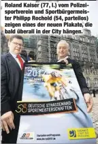  ??  ?? Roland Kaiser (77, l.) vom Polizeispo­rtverein und Sportbürge­rmeister Philipp Rochold (54, parteilos) zeigen eines der neuen Plakate, die bald überall in der City hängen.