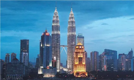  ?? GOH SENG CHONG/BLOOMBERG ?? The Petronas Twin Towers stand illuminate­d against the skyline at dusk in Kuala Lumpur, Malaysia. Despite efforts to save the liquefied natural gas project in B.C., Malaysian oil giant Petronas and its Pacific NorthWest LNG partners lost hope in its...