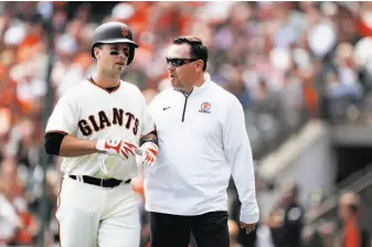  ?? Carlos Avila Gonzalez / The Chronicle ?? Buster Posey is walked off the field by Giants head trainer Dave Groeschner after the catcher was hit in the head by a 94 mph fastball from Arizona’s Taijuan Walker on Monday.