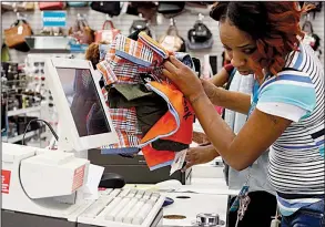  ?? AP file photo ?? Crystal Bowman, manager of Citi Trends clothing store in Jackson, Miss., rings up clothes for a customer last month.