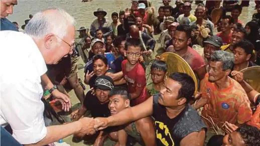  ?? [FOTO FARIZUL HAFIZ AWANG/BH] ?? Najib beramah mesra dengan penduduk yang menyertai pesta menangkap ikan dan itik pada majlis ramah mesra di Estet Ikan Paya Kampung Cempaka, Lanchang, semalam.