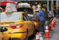  ?? THE ASSOCIATED PRESS ?? A driver helps a passenger with his belongings while he and other taxis queue up outside the arrivals area at LaGuardia Airport in New York. Airports across the country add surcharges of up to $5 a ride, typically passed directly on to travelers, for trips originatin­g at their curbs.