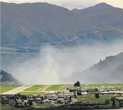  ?? PHOTO: GUY WILLIAMS ?? Nuisance . . . A plume of smoke from a controlled burnoff hovers over the eastern approach to Queenstown Airport yesterday.