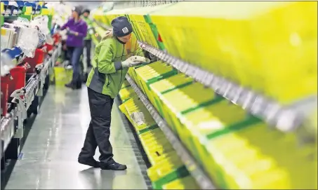  ?? [CHRIS RATCLIFFE/BLOOMBERG NEWS] ?? An employee picks an order at the Ocado Group distributi­on center in Dordon, England. Kroger has partnered with Ocado to bring the online grocery ordering system to the United States.