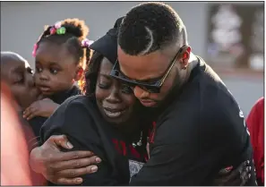  ?? ?? Kimberly Blackshire-Lee (photo at left), mother of Bradley Blackshire, embraces his cousin Montrell Ussery during a vigil on March 16, 2019, at the spot where her son was killed by a Little Rock police officer. Blackshire-Lee (photo above, third from right), her husband, DeAngelo Lee (fourth from right), and others pray during an April 22, 2019, protest at the state Capitol in Little Rock.