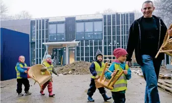  ?? RP-FOTO: OLAF STASCHIK ?? Die Mädchen und Jungen packen tatkräftig mit an und tragen, was sie tragen können: Bernhard Kern vom Vorstand zeigt ihnen den Weg. Der ist nicht weit, denn der Neubau liegt direkt hinter dem Altbau.