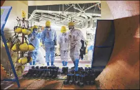  ?? EPA ?? Inspection officers enter the containmen­t vessel of the Unit 5 reactor building at the tsunami-crippled Fukushima Dai-ichi nuclear plant in Futaba on Friday.