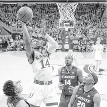  ?? Jamie Squire / Getty Images ?? Malik Newman, who led Kansas with 22 points, shoots over Kansas State’s Kamau Stokes, left, Makol Mawien (14) and Xavier Sneed (20) during Friday’s Big 12 semifinal game.