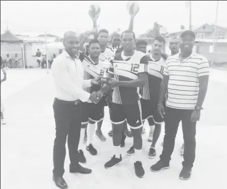  ??  ?? Gifford Marshall, Mayor of Bartica hands over the winning trophy to Bartica Warriors on Sunday in the presence of DVA president Trevor Williams.