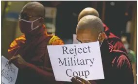  ??  ?? Buddhist monks display placrds during a protest march against the military coup in Yangon.