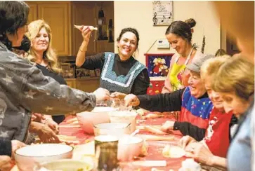  ?? MEG MCLAUGHLIN U-T ?? Yvette Helfers of El Cajon raises a tamale, above, to use as an example as she and her family make more than 200 tamales together on Dec. 14 in Santee. More photos of the traditiona­l holiday gathering are shown below.