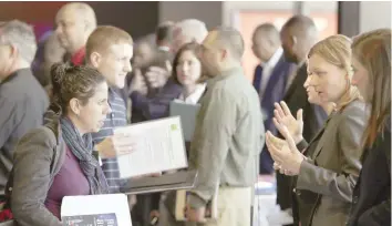  ?? — Reuters ?? Legal firm Hogan Lovells representa­tive Nina LeClair (2nd R) talks to US military veteran applicants (L) at a hiring fair for veteran job seekers and military spouses at the Verizon Center in Washington.