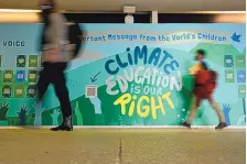  ?? ALASTAIR GRANT/ASSOCIATED PRESS ?? People walk past a wall with a message on climate education at the COP26 U.N. Climate Summit on Sunday in Glasgow, Scotland.